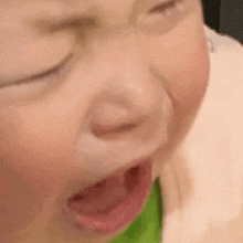 a close up of a baby 's face with his eyes closed and his mouth open .