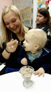 a woman feeds a child a spoonful of ice cream