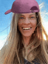 a woman wearing glasses and a purple hat is smiling