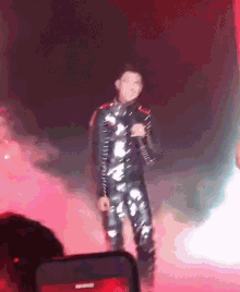 a man singing into a microphone on a stage in front of a red background