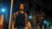 a man in a plaid shirt is standing in front of a pole