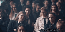 a group of girls in school uniforms are sitting in a classroom and one of them says she 's such a dick .