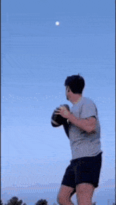 a boy in a grey shirt is standing in front of a blue sky