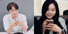 a man and a woman are looking at their phones and smiling .