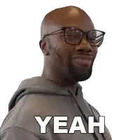 a man wearing glasses and a grey hoodie has the word yeah on his face