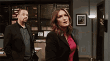 a man in a suit and a woman in a pink shirt are standing next to each other