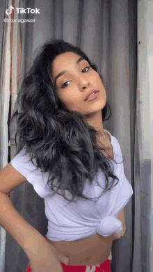a woman wearing a white crop top and red shorts has a tiktok account .