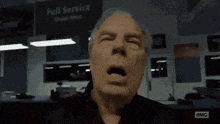 a man is yawning in front of a sign that says " full service "