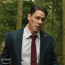 a man in a suit and tie is standing in the woods with a prime arrow in the background