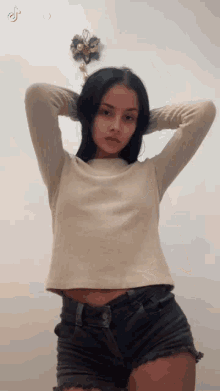 a woman in a crop top and shorts is standing in front of a wall .