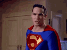 a man in a superman costume is standing in a room .
