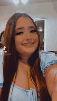 a woman with long hair is smiling and taking a selfie in a room .