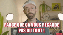a man wearing glasses and a hat says " parce que ca vous regarde pas du tout ! "
