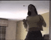 a woman is standing in a room with her arms outstretched and her breasts visible .