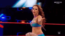 a woman in a bikini is standing in a wrestling ring with a w logo on the ring .
