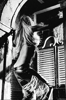 a black and white photo of a naked woman standing in a doorway