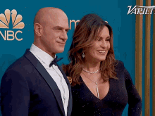 a man and a woman are posing for a picture in front of a variety logo