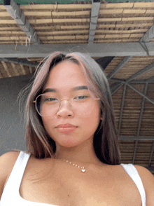 a woman wearing glasses and a white tank top poses for a picture