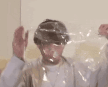 a man is holding a plastic bag over his head with his face covered in plastic .