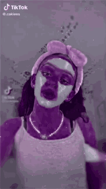 a woman is applying makeup to her face while wearing a headband with a bow .