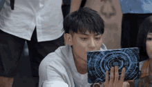 a young man is looking at a tablet with a blue circle on the screen