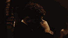 a man in a tuxedo holds his hand to his face