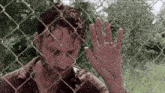 a man is behind a chain link fence with his hand on the glass