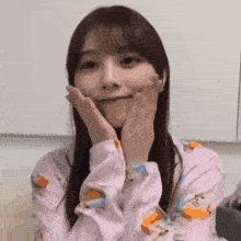 a woman in a pink shirt is making a face with her hands .