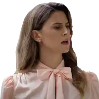 a woman in a pink shirt with a bow on the neck looks surprised