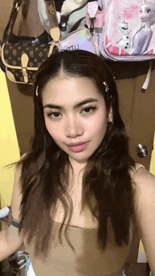 a woman is taking a selfie in front of a bunch of bags hanging on a wall .