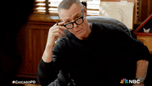 a man wearing glasses and a black shirt is sitting in a chair