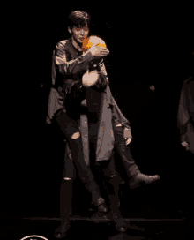 two men are dancing on a stage in a dark room .