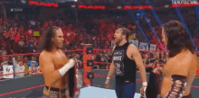 a group of wrestlers are standing on a wrestling ring talking to each other .