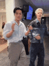a man in a denim jacket is holding a microphone while dancing with another man