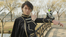 a man in a black and gold outfit is standing on a bridge pointing
