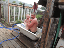 a man and a baby are playing in a bathtub outside