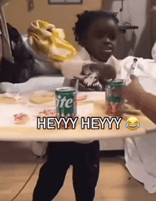 a little girl is sitting at a table with a can of sprite and a jar of gummy bears .