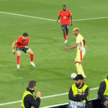 soccer players on a field with a man in a yellow vest that says ward k9