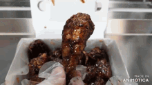 a person is holding a piece of chicken in a box that says made in animotica on the bottom