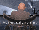 a man in a suit sits in a chair with the words we meet again in the jar below him