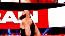 a wrestler is standing in front of a large red and white banner that says raw