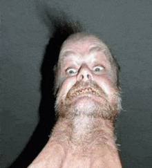 a man with a beard and mustache is making a funny face with his mouth open .