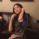 a woman wearing headphones sits on a couch next to a phone