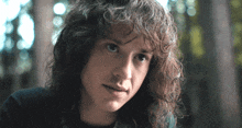 a man with long curly hair looks at the camera