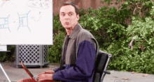 a man is sitting in a chair using a laptop computer .