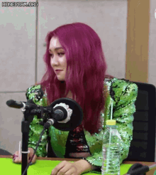 a woman with purple hair is sitting in front of a microphone