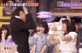 a group of women are standing next to each other in front of a man in a suit .