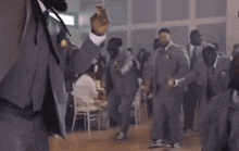 a man in a suit is kneeling down on the floor with his arms in the air