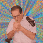 a man with glasses is sitting in front of a microphone with a colorful background