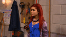 a woman with red hair stands in front of a wall that has a sign that says " do not warning labels "